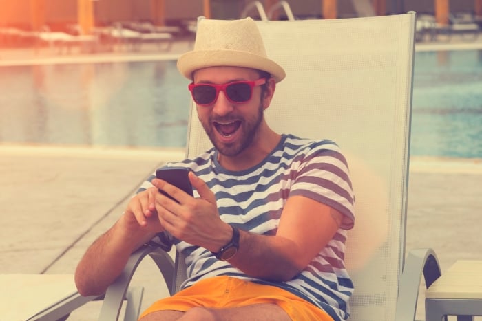 Happy man with phone by the pool